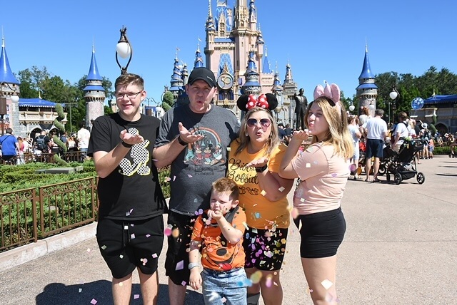 Lauren Hersey at Disney world with family posing in front of castle at Magic Kingdom wearing Disney outfits