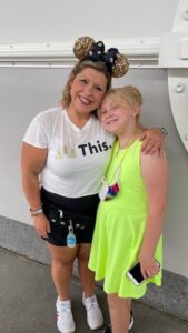 Lauren Hersey with daughter at Disney world wearing magic kingdom outfit with gold mouse ears