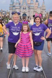 Lauren Hersey at Disney World at Magic Kingdom posing in front of the castle wearing matching alice and wonderland outfits with mother and daughter 
